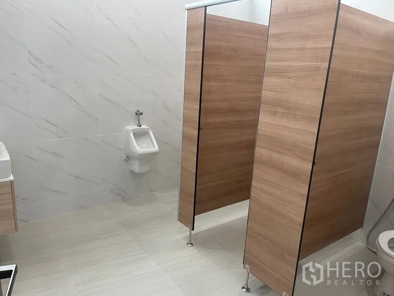 Home Office for rent or sale in Wang Thonglang, Bangkok - Restroom view showing wooden partitions, urinal and sink area.