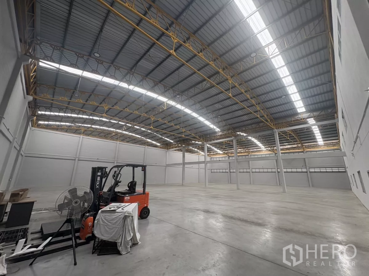 Factory for rent in Bang Phli, Samut Prakan - Large warehouse interior with high arched roof and a forklift on concrete floor.