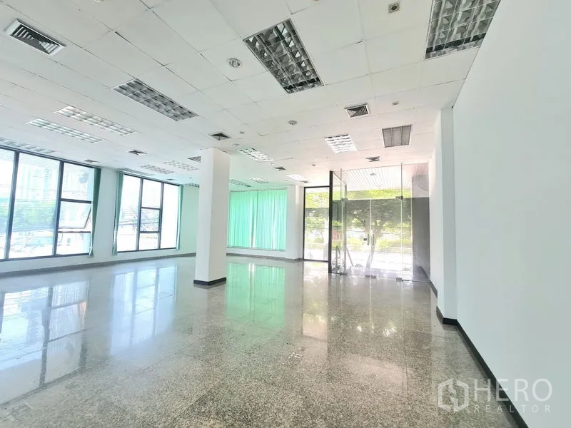 Retail Space for rent in Sathon, Bangkok - Bright corner of the shop with glass entrance doors, ceiling lighting, and tall windows fitted with green vertical blinds.
