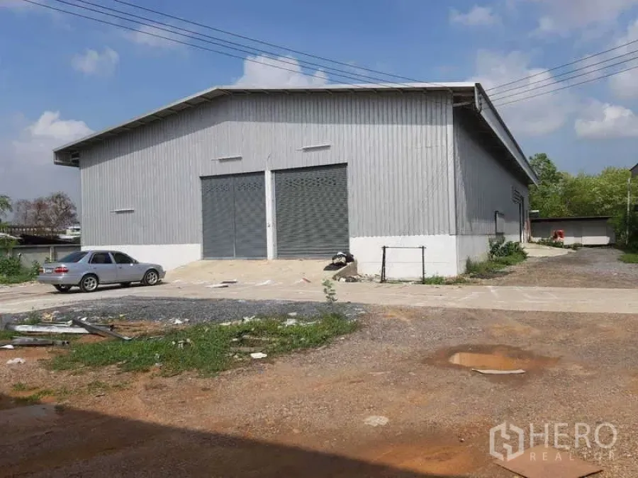 Warehouse for rent in Khlong Luang, Pathum Thani - Metal-clad warehouse exterior with twin roller shutter doors, driveway access and on-site parking.