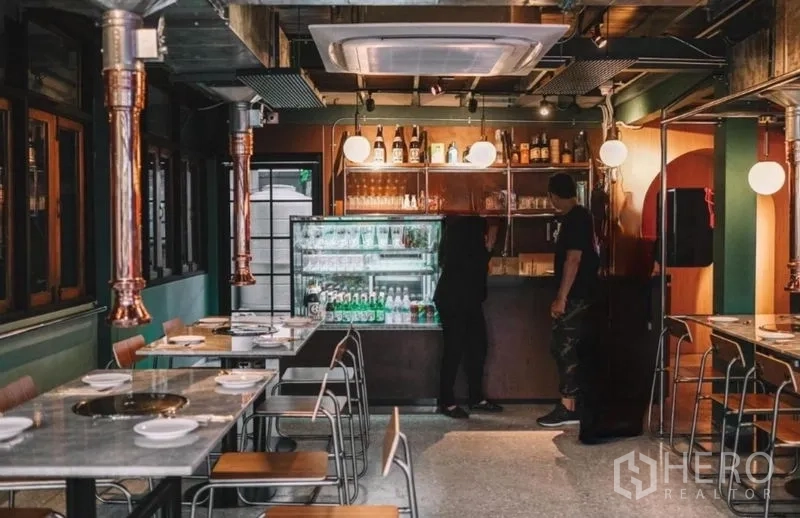 Detached House for sale in Khlong Toei, Bangkok - Bar area with beverage display fridge, shelving and modern lighting beside neatly arranged dining tables.