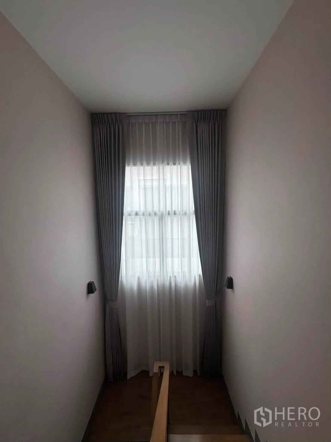 Detached House for rent or sale in Prawet, Bangkok - Stairwell with tall window, sheer and grey curtains, and a wooden handrail.