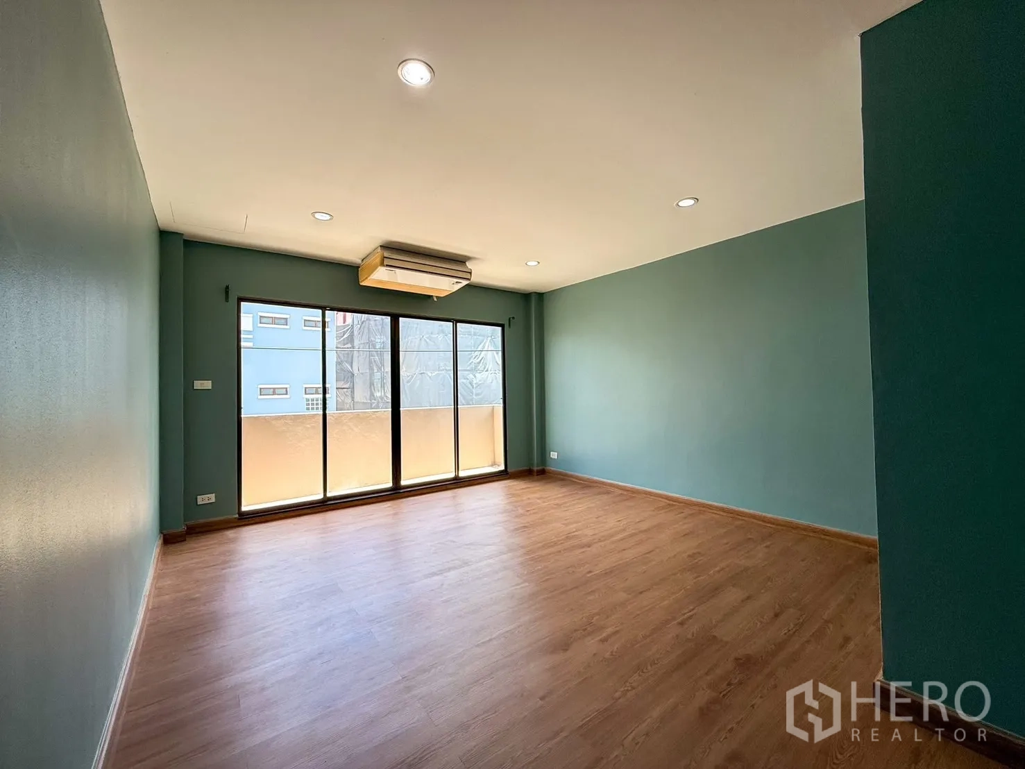 Home Office for rent in Wang Thonglang, Bangkok - Spacious room with sliding glass doors to a small balcony and wood floors.