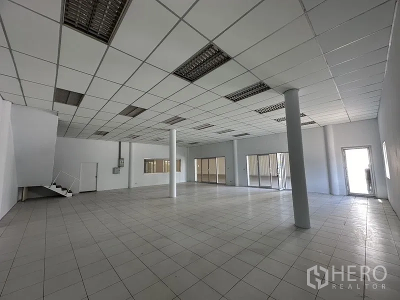 Factory for rent in Khlong Luang, Pathum Thani - Open-plan office space with columns, staircase, and multiple glass entrances for meeting rooms.