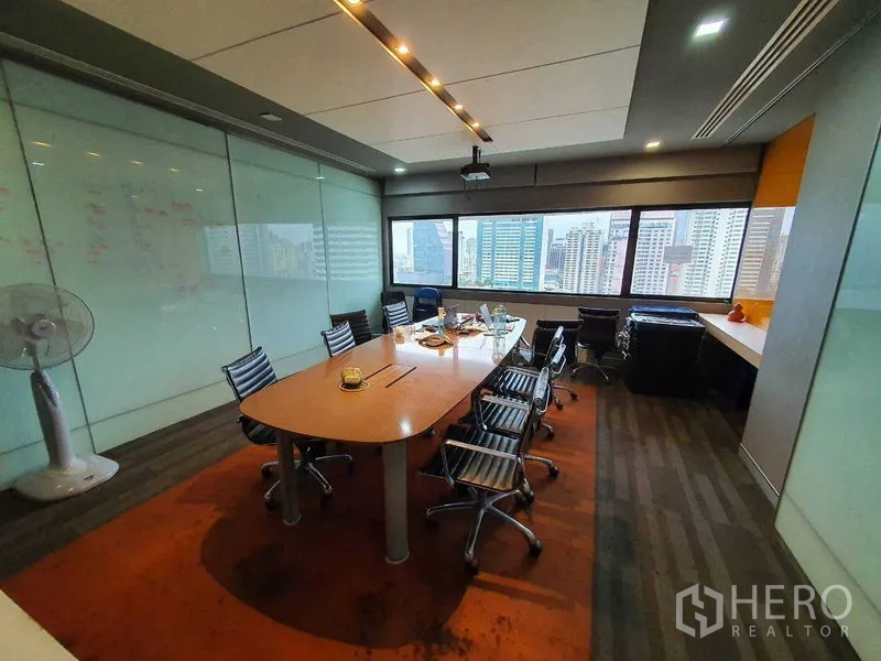 Office Space for rent in Watthana, Bangkok - Conference room with long table, swivel chairs, projector and skyline view through large windows.