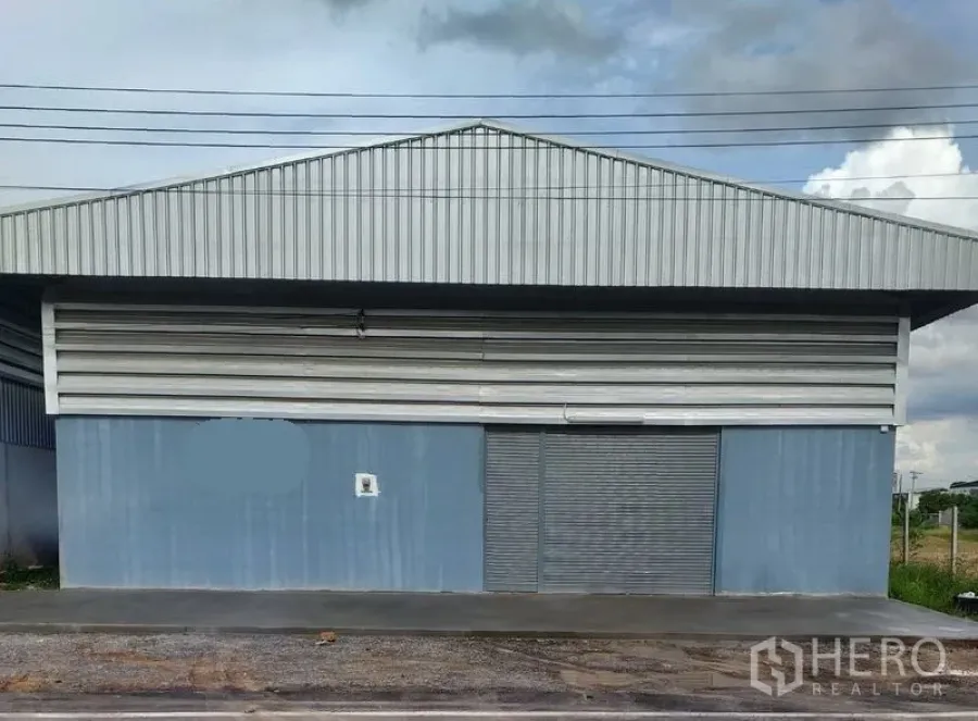 Warehouse for rent in Bang Yai, Nonthaburi - Front facade of the warehouse with gable metal roof, large roller door and paved frontage.