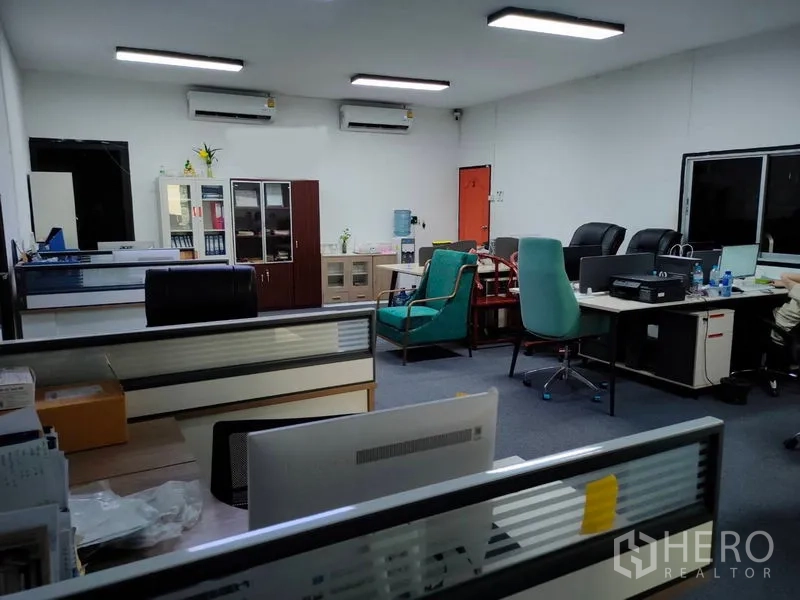 Warehouse for rent in Bang Kapi, Bangkok - Air-conditioned office inside the warehouse with multiple desks, cabinets, and large windows.