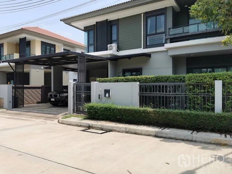 Detached House for rent or sale in Lam Luk Ka, Pathum Thani - Street view of contemporary home with metal fence and manicured hedge