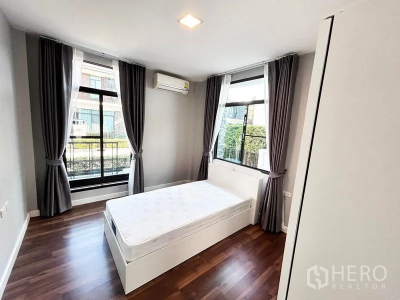 Detached House for rent or sale in Prawet, Bangkok - Corner bedroom with garden views, bed, and air-conditioning.