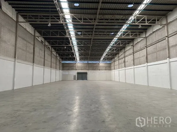 Factory for rent in Si Racha, Chon Buri - Vast empty warehouse interior with high ceiling, skylights and smooth concrete floor.