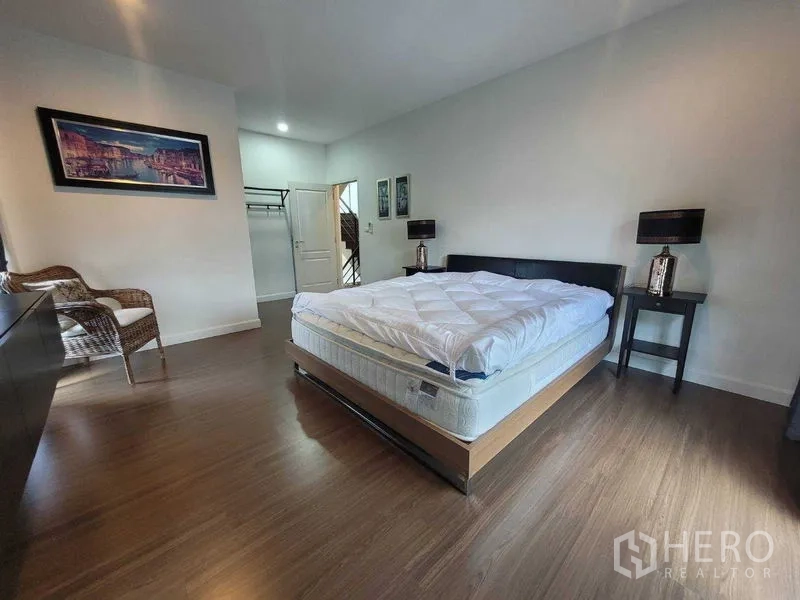 独立式住宅 出租或出售在Prawet, Bangkok - 宽敞主卧，木地板、床与床头柜。