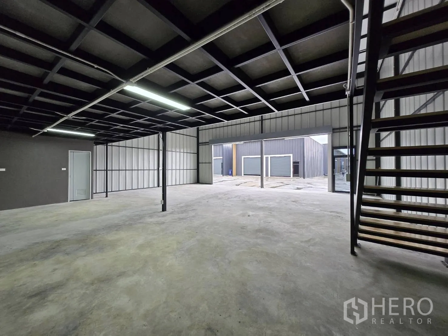 Warehouse for rent - Ground floor area beneath the mezzanine with metal staircase and outlook to the loading yard.