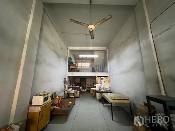 Shophouse for sale in Phra Khanong, Bangkok - Deep ground‑floor shop hall with high ceiling, mezzanine level and ceiling fan.