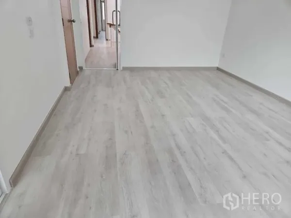 Townhouse for rent in Khlong Toei, Bangkok - Spacious empty room with pale laminate floors and white walls, ready for flexible use.