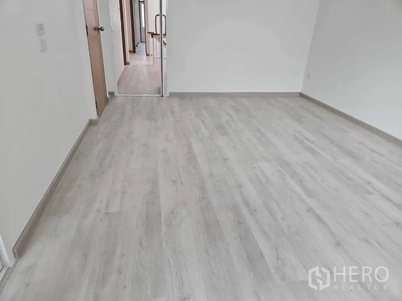 Townhouse for rent in Khlong Toei, Bangkok - Spacious empty room with pale laminate floors and white walls, ready for flexible use.
