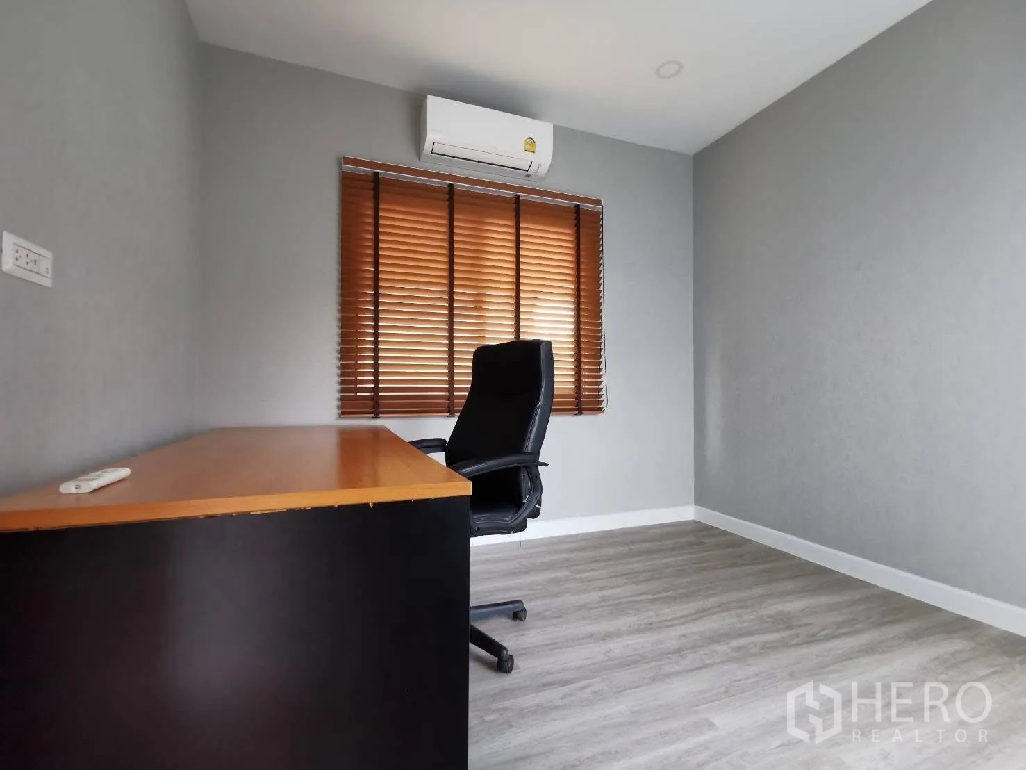 Detached House for rent in Bang Phli, Samut Prakan - Home office with desk and swivel chair, gray walls, wood-style flooring, and window blinds.