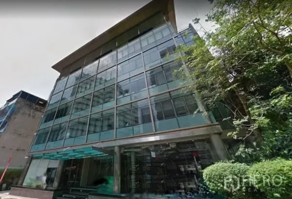 办公空间 出租在Khlong Toei, Bangkok - 现代玻璃幕墙写字楼外观，带入口雨棚与绿化景观，坐落于曼谷。