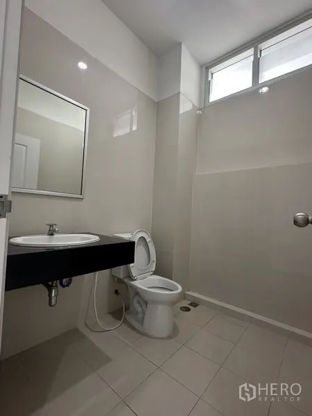 Factory for rent in Bang Phli, Samut Prakan - Clean restroom with white tiles, sink, mirror and toilet, plus a high window for ventilation.