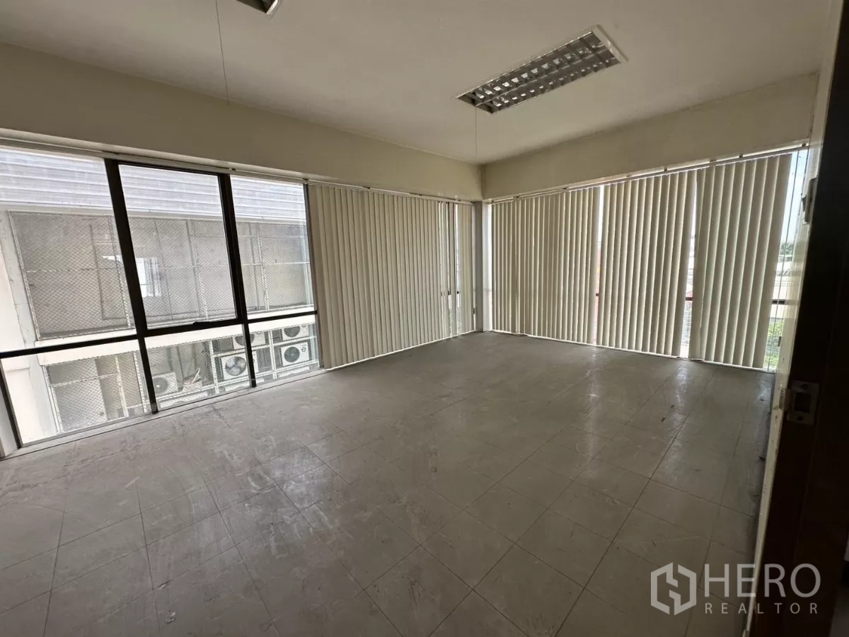 Warehouse for rent in Suan Luang, Bangkok - Medium office room with wraparound windows, vertical blinds, and view of adjacent AC units.