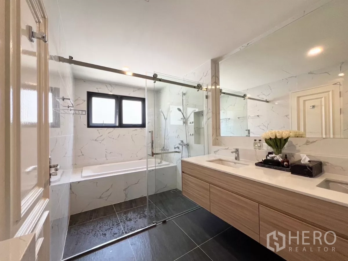 Detached House for rent in Bang Phli, Samut Prakan - Modern bathroom with double vanity, glass shower and bathtub with marble tiles.