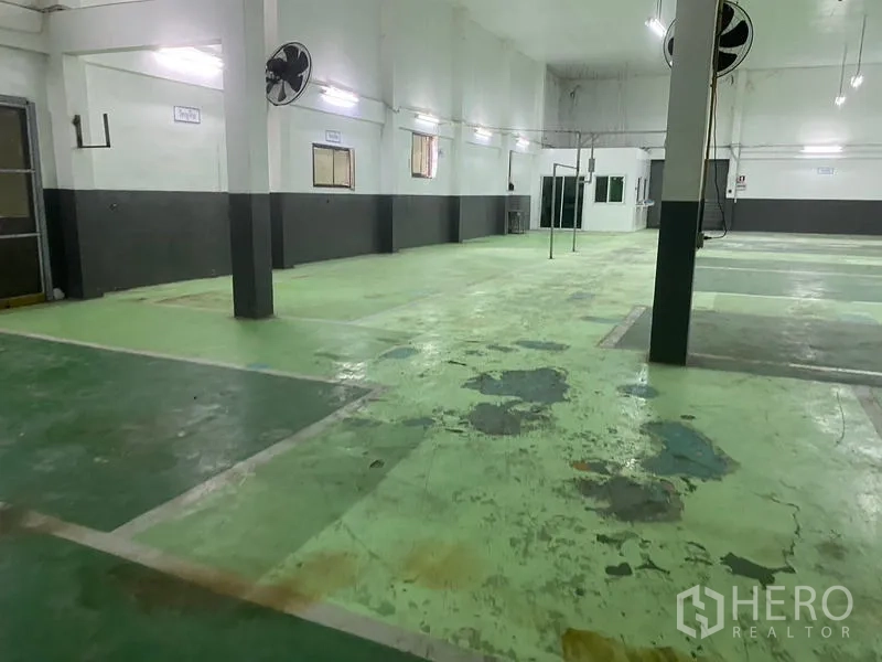 Warehouse for rent in Lam Luk Ka, Pathum Thani - Spacious warehouse interior with high ceiling, fans and marked green epoxy floor