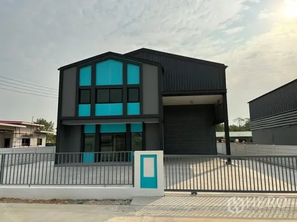 Factory for rent or sale in Bang Bua Thong, Nonthaburi - Front view of a modern mini factory with teal-accented two‑storey office and wide roller shutter in a gated yard.