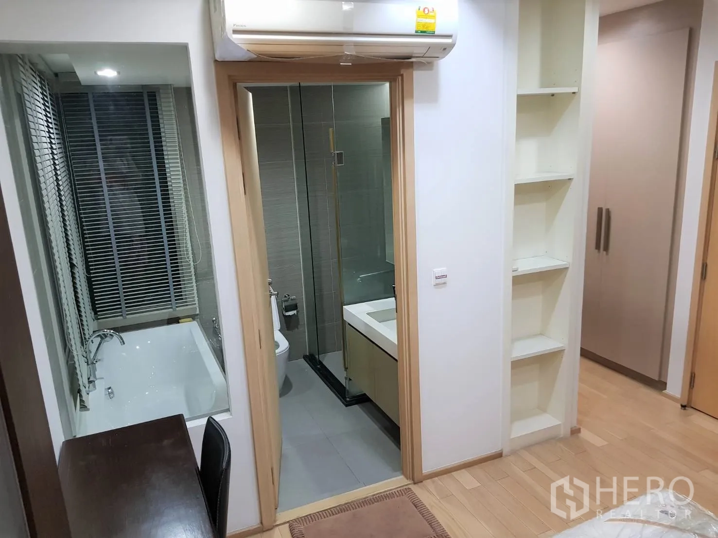Condominium for rent in Khlong Toei, Bangkok - Hallway view to a bathroom with vanity, toilet and a separate bathtub behind window blinds.
