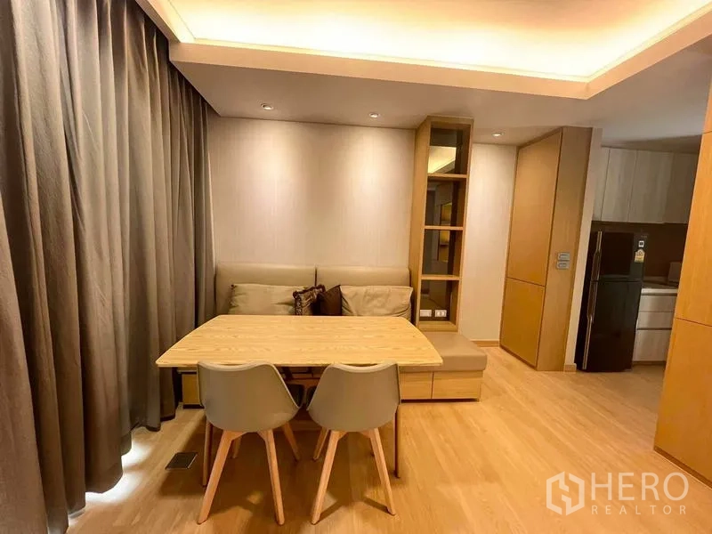 Condominium for rent or sale - Dining corner with sofa seating, wooden table, and ceiling cove lighting.