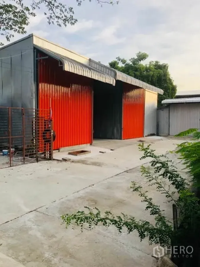 货栈 出租在Wang Thonglang, Bangkok - 仓库外观，醒目的红色金属推拉门，宽阔混凝土场地与雨棚屋檐。