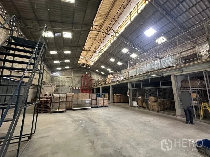 Factory for rent in Lam Luk Ka, Pathum Thani - High-ceiling warehouse floor with skylights, mezzanine, and metal stairs.