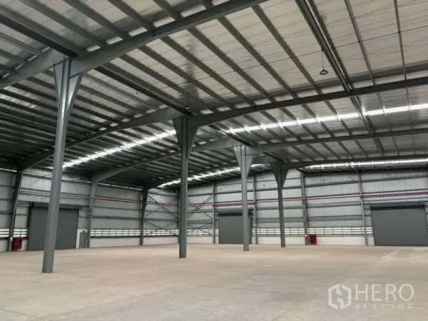 Warehouse for rent in Nikhom Phatthana, Rayong - Open-span warehouse space with skylights, steel columns, and multiple loading doors