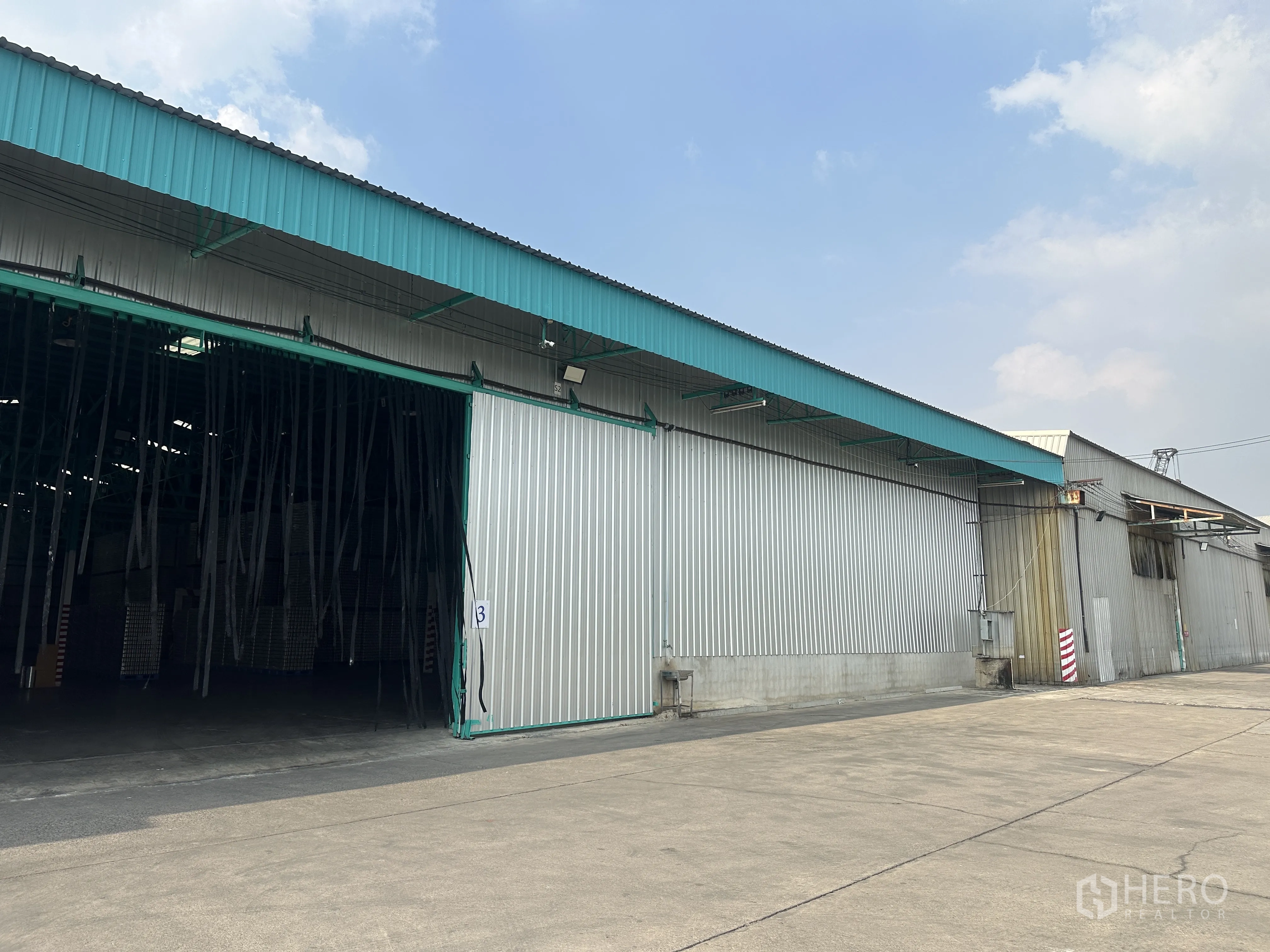 Warehouse for rent in Mueang Pathum Thani, Pathum Thani - Side view of warehouse block in a secure compound with ample truck turning space and loading access.