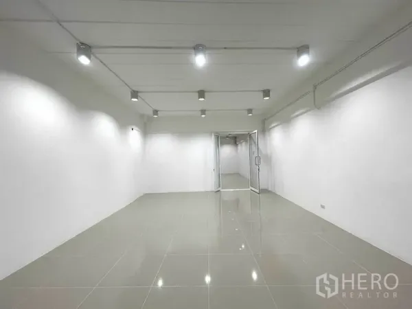 Office Space for rent in Khlong Toei, Bangkok - Bright open-plan office with white walls, glossy tile floors and ceiling spotlights leading to a glass door.