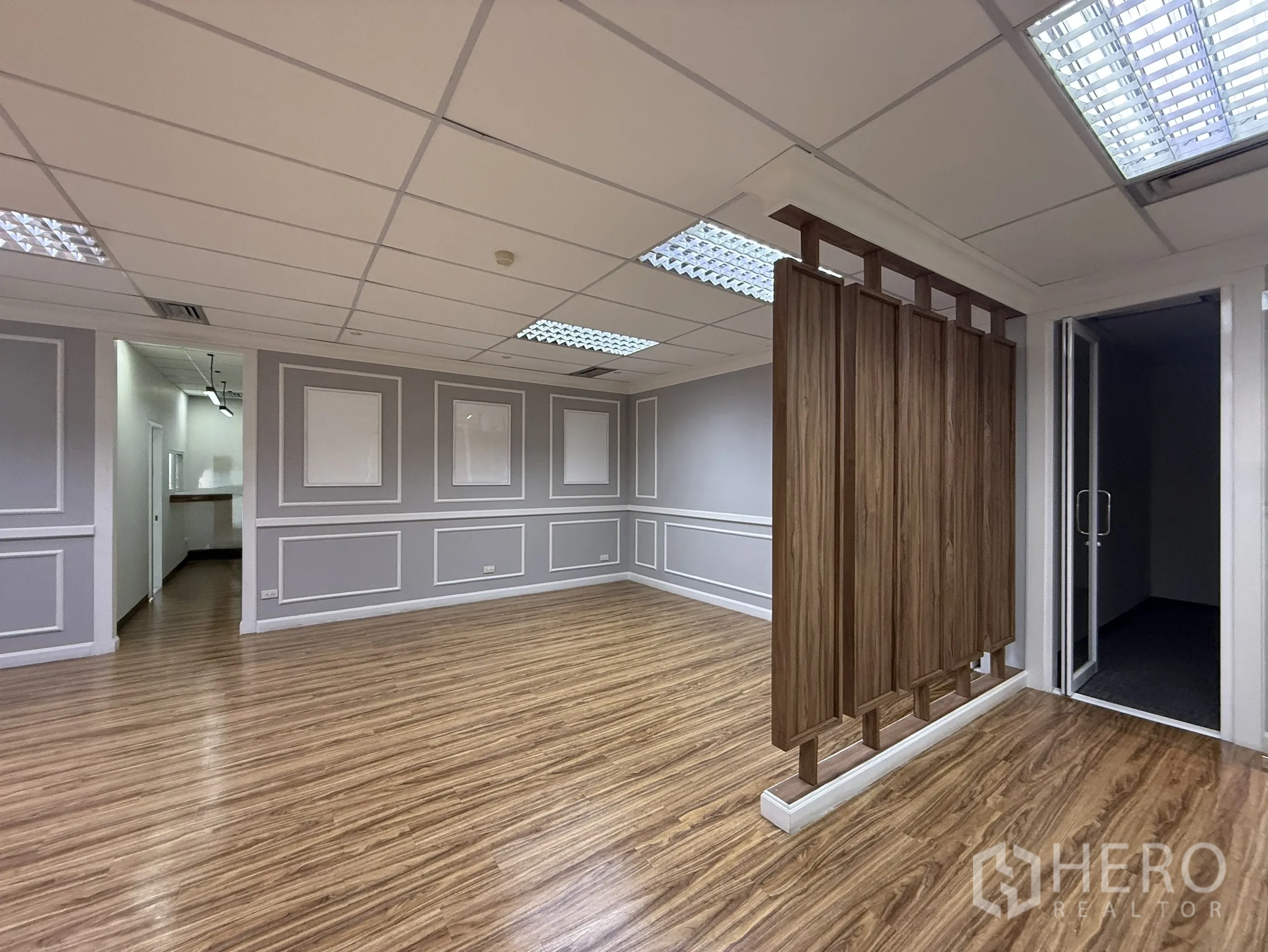 Office Space for rent - Open workspace featuring a wooden screen divider, paneled walls and wood floors leading to meeting rooms.