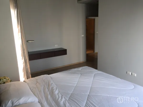 Condominium for rent in Bangkok - Master bedroom with floating console and doorway to an en-suite bathroom.