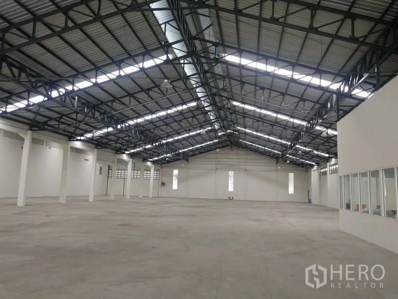 Warehouse for rent in Phra Pradaeng, Samut Prakan - Clear‑span storage hall with high ceilings, skylight strips and white perimeter walls for efficient racking.
