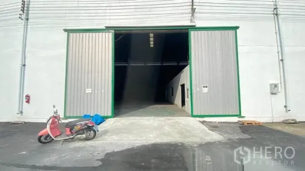 Warehouse for rent in Samut Prakan - Wide sliding metal doors and ramp at the front of a warehouse bay.