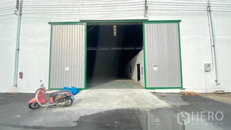 Warehouse for rent in Samut Prakan - Wide sliding metal doors and ramp at the front of a warehouse bay.