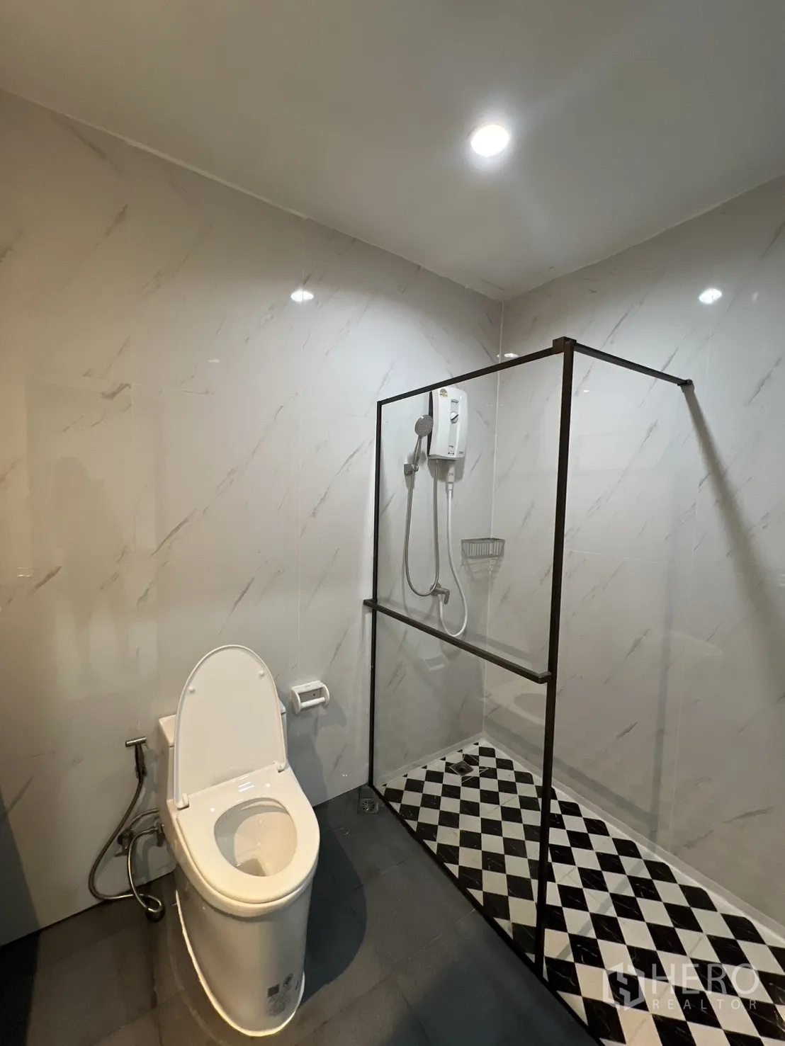 Townhouse for rent in Watthana, Bangkok - Bathroom with glass-enclosed shower and checkerboard floor next to the toilet.