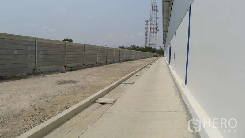 Warehouse for rent in Bang Phli, Samut Prakan - Exterior side walkway and service lane beside the warehouse with a concrete perimeter wall.