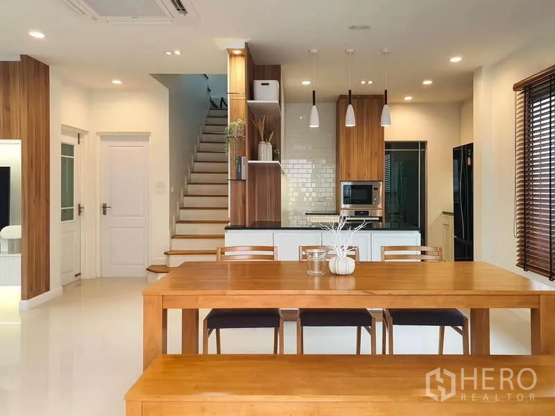 Detached House for rent in Sathon, Bangkok - Open-plan dining area and kitchen with pendant lights and a staircase to the upper floor.
