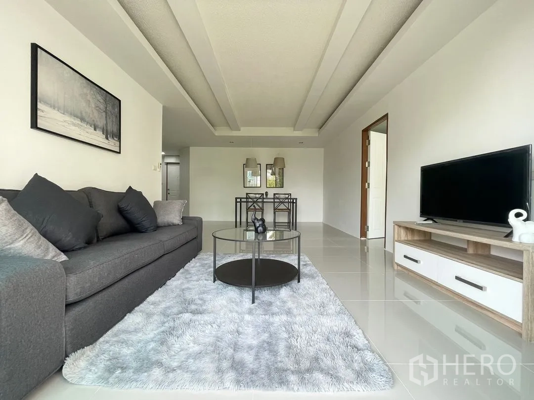 Condominium for rent in Khlong Toei, Bangkok - Wide living room view showing sofa, TV stand, and dining set in the back.