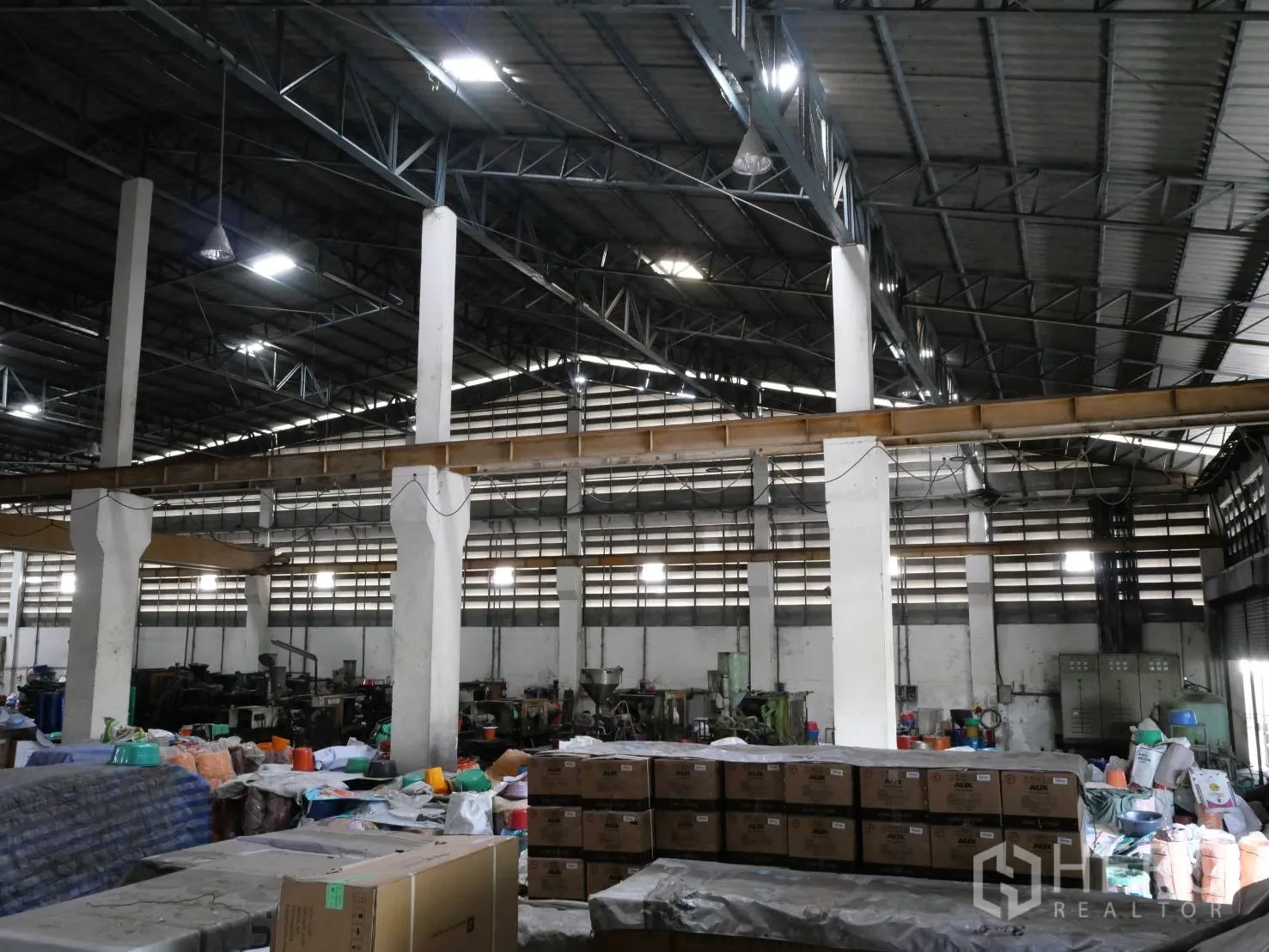 Factory for rent or sale in Bang Khun Thian, Bangkok - Open-span hall with tall columns, overhead crane rails and packed cartons.