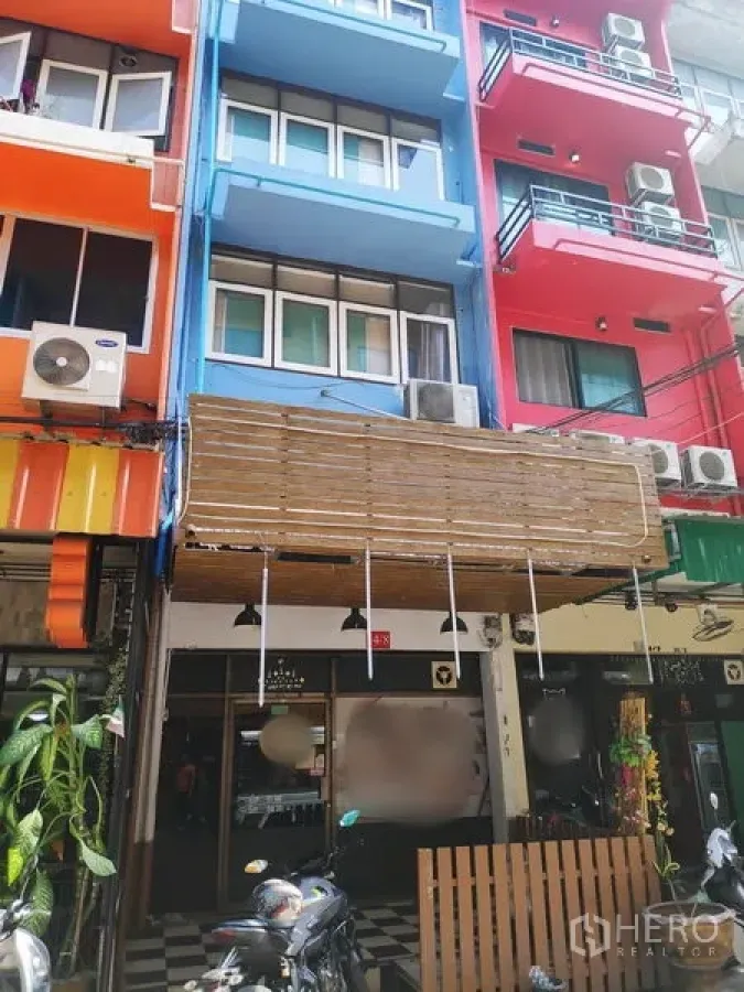 Townhouse for rent in Sathon, Bangkok - Colorful shophouse row with a blue multi‑storey townhouse, balconies, awning and streetfront AC units.
