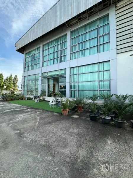 Warehouse for rent in Bang Phli, Samut Prakan - Glass-front office facade of the warehouse with small garden and outdoor seating.