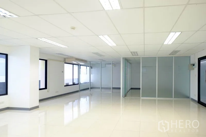 Office Space for rent in Chatuchak, Bangkok - Open-plan office with white tiled floors, drop ceiling lights and glass partitions.