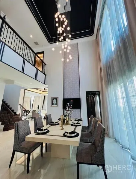 Detached House for rent or sale in Watthana, Bangkok - Double-height dining room with a long table and statement pendant lights.