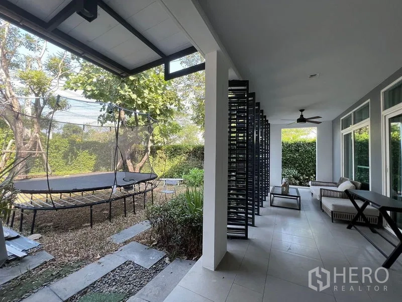 Detached House for sale - Shaded terrace with seating and ceiling fan opening to a private garden with mature trees and trampoline.