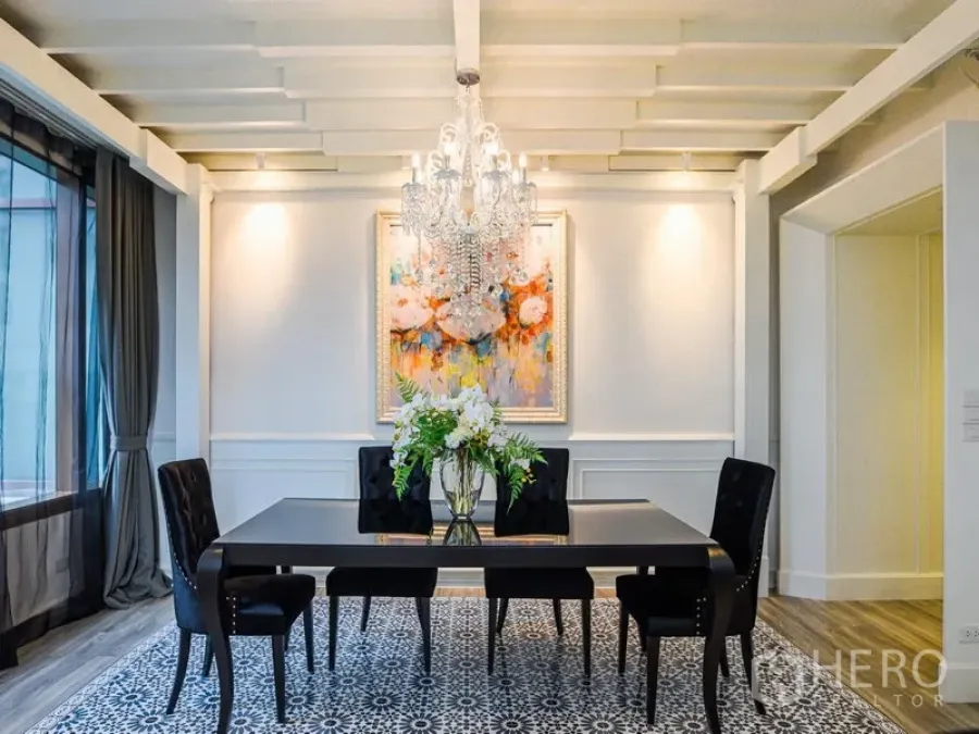 Condominium for rent or sale in Khlong Toei, Bangkok - Elegant dining room with crystal chandelier, black table and four chairs, patterned rug, and wall art.