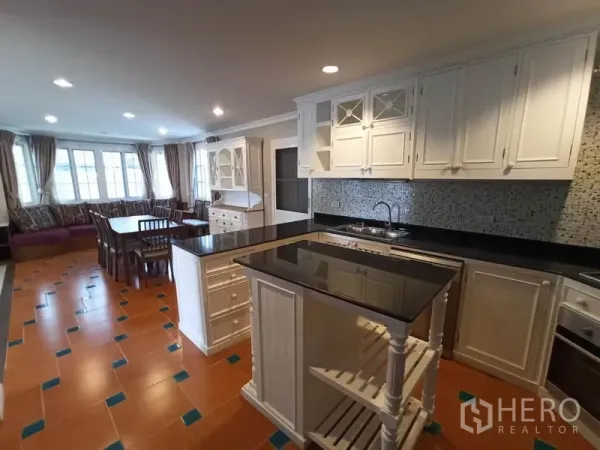 Detached House for rent in Mueang Samut Prakan, Samut Prakan - Fully fitted kitchen with white cabinetry, black granite countertops, island and mosaic backsplash.